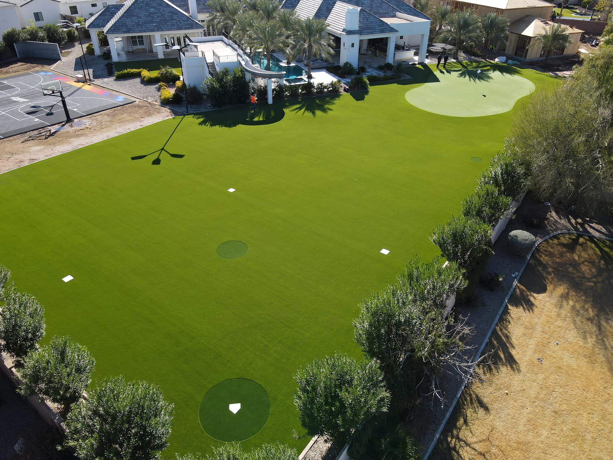 backyard landscaped with synthetic turf and a putting green